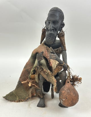 1413501 MAKONDE CARVED WOOD MALE FIGURE SEATED ON STOOL WITH FIBER CLOTH, KENYA